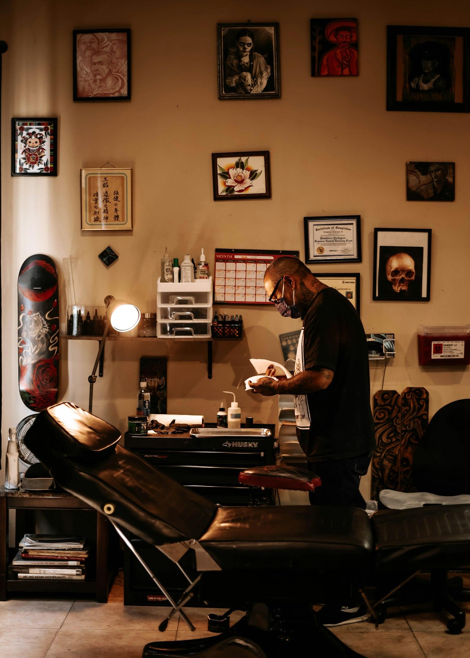 Tattoo artist at a station with a chair, lamp, and ink bottles